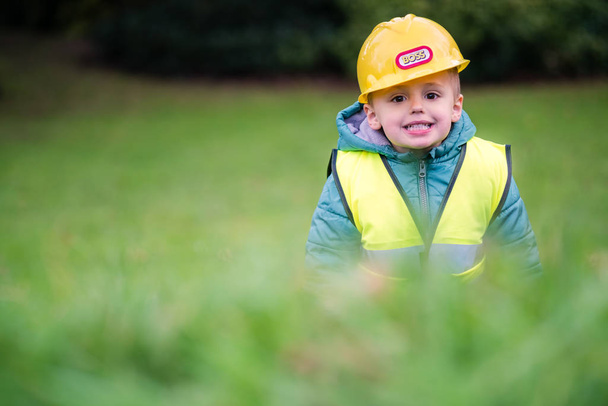 Pieni söpö poika teeskentelee olevansa rakentaja työnjohtaja kotipuutarhansa ulkopuolella
 - Valokuva, kuva