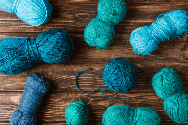 top view of green and blue knitting yarn clews on wooden surface - Zdjęcie, obraz