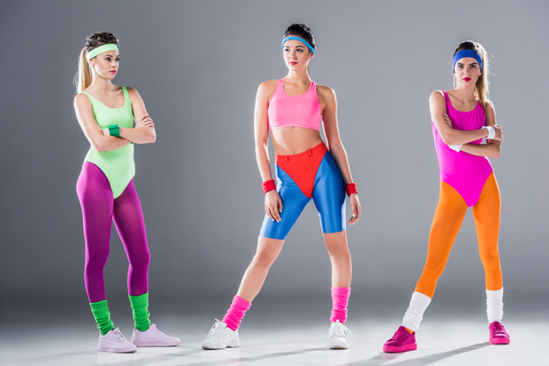 full length view of athletic young women in 80s style sportswear posing on grey - Zdjęcie, obraz