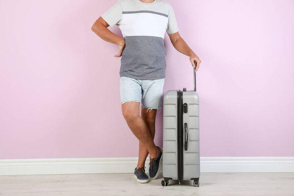 Senior man with suitcase near color wall. Vacation travel - Фото, изображение
