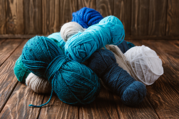 vista de perto de fios brancos, azuis e verdes para tricotar na superfície de madeira
 - Foto, Imagem