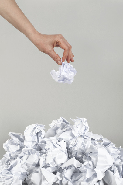 Stack of crumpled paper balls and hand on gray - Foto, afbeelding