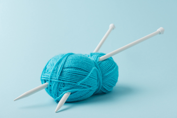 vue rapprochée du fil bleu griffe et aiguilles à tricoter sur fond bleu
 - Photo, image