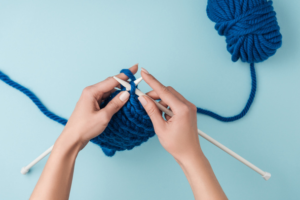 ritagliato colpo di donna che lavora a maglia su sfondo blu con filato blu
 - Foto, immagini