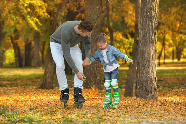 Young father and his daughter roller skating in autumn park - Photo, Image