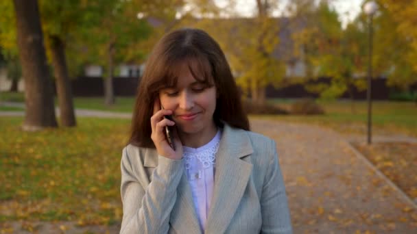 teléfono móvil caminando por el parque de otoño y sonriendo
 - Metraje, vídeo