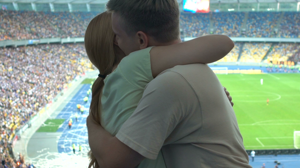 Couple hugging at stadium, romantic marriage proposal during football match - Кадры, видео