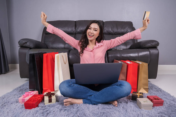 fröhliche Frau mit Laptop zum erfolgreichen Online-Shopping mit Kreditkarte im Wohnzimmer - Foto, Bild