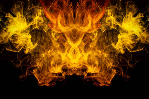 Mocap for cool t-shirts. Thick colorful yellow and orange smoke  in the form of a monster on a black isolated background. Background from the smoke of vape - Photo, Image