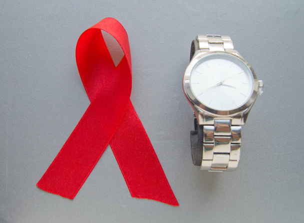 Παγκόσμια ημέρα κατά του Aids, το σύμβολο της κόκκινης κορδέλας και το ρολόι - μην σπαταλήστε το χρόνο για να ξεκινήσετε τη θεραπεία - Φωτογραφία, εικόνα
