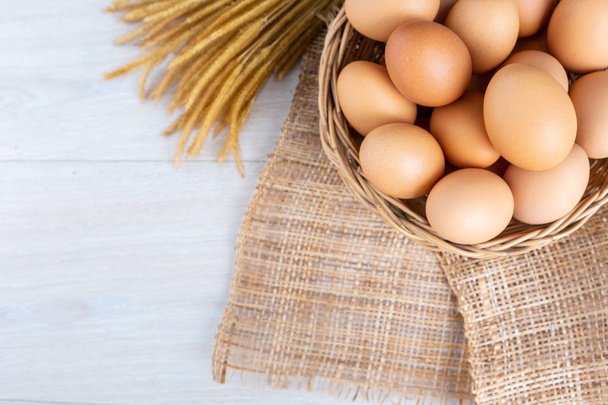 Eggs in a wooden basket on a white wooden table. - Photo, Image