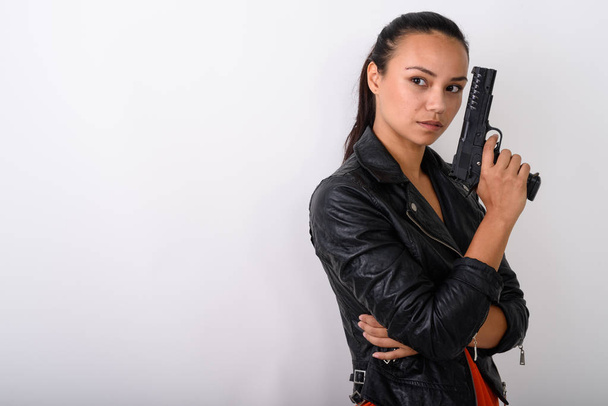 Studioaufnahme einer jungen asiatischen Frau, die im Besitz einer Handfeuerwaffe denkt  - Foto, Bild