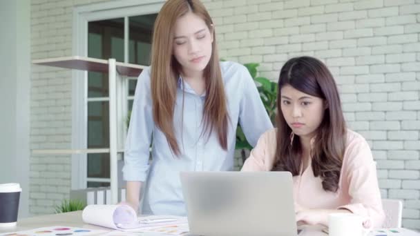 Привлекательные умные творческие азиатские деловые женщины в элегантной повседневной одежде, работающие на ноутбуке, сидя за столом на рабочем столе. Женщины работают в офисной концепции
. - Кадры, видео