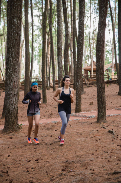 two sporty woman ran in the forest at summer - Foto, imagen