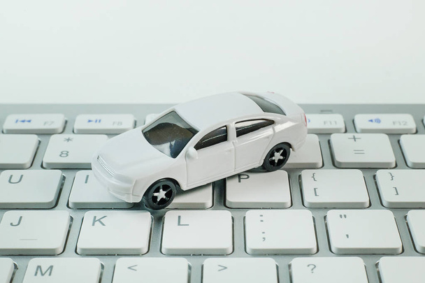 weißes Spielzeugauto auf Tastatur-Computer Nahaufnahme Bild Hintergrund. - Foto, Bild