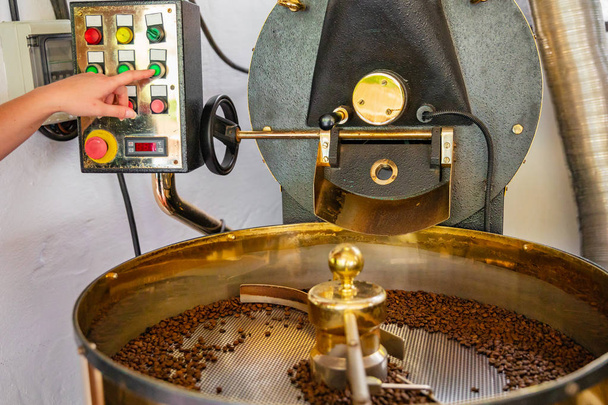Employee feminino pressionando botão de máquinas no torrador de café
 - Foto, Imagem