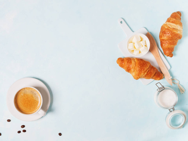 Cup of espresso with capsules, croissants, coffee beans and butter on blue pastel background  - Foto, afbeelding