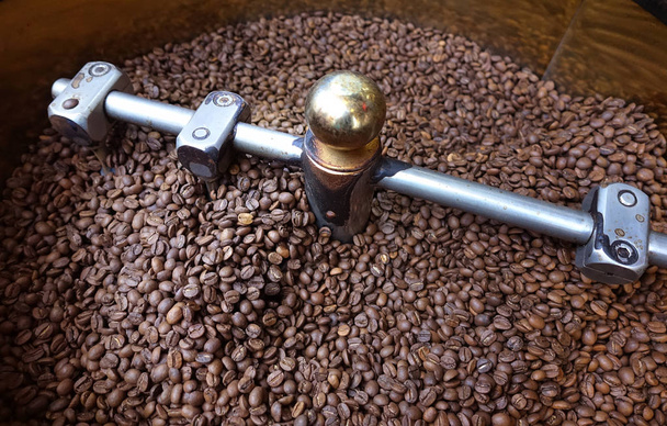 pilha de grãos de café marrom em torrador
  - Foto, Imagem