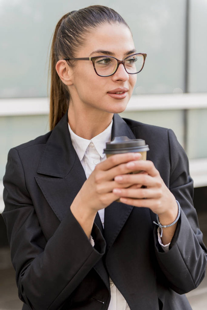 Portrait de jeune femme d'affaires utilisant un téléphone portable et buvant du café pendant une pause à l'extérieur
 - Photo, image