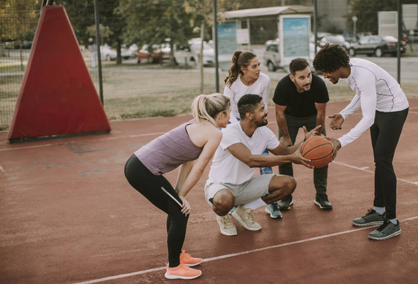 Группа мультиэтнических молодых людей, играющих в баскетбол на площадке
 - Фото, изображение