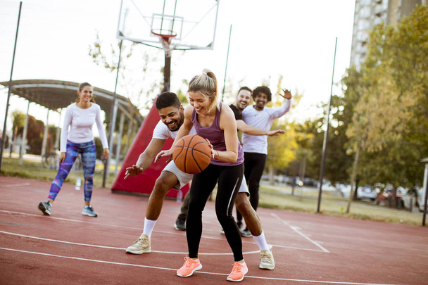 Groupe de jeunes multiraciaux jouant au basket sur le terrain à l'extérieur
 - Photo, image