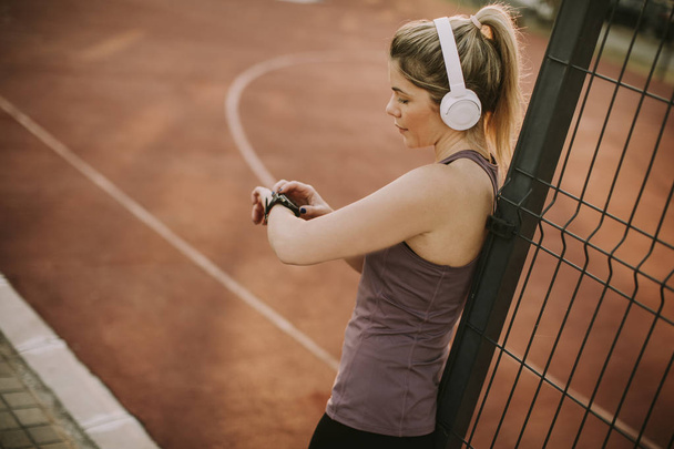 Sportwoman controle van puls aan slimme horloge geschiktheidsapparaat bij buiten - Foto, afbeelding