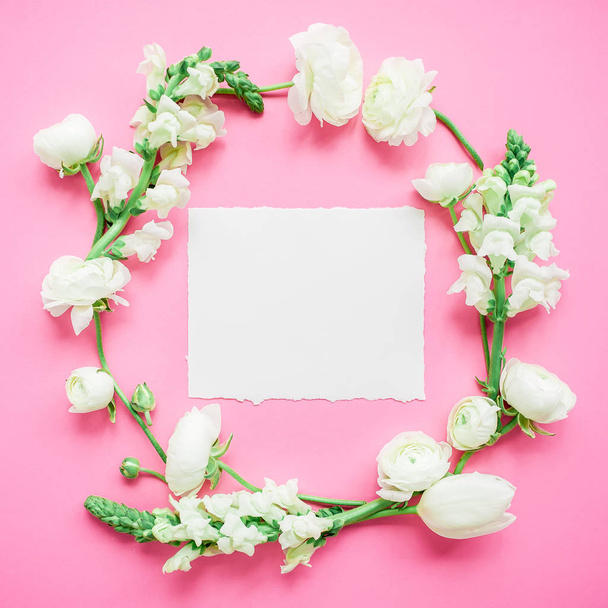 Floral round frame of white flowers with paper postcard on pink background. Flat lay, top view. - Foto, Bild