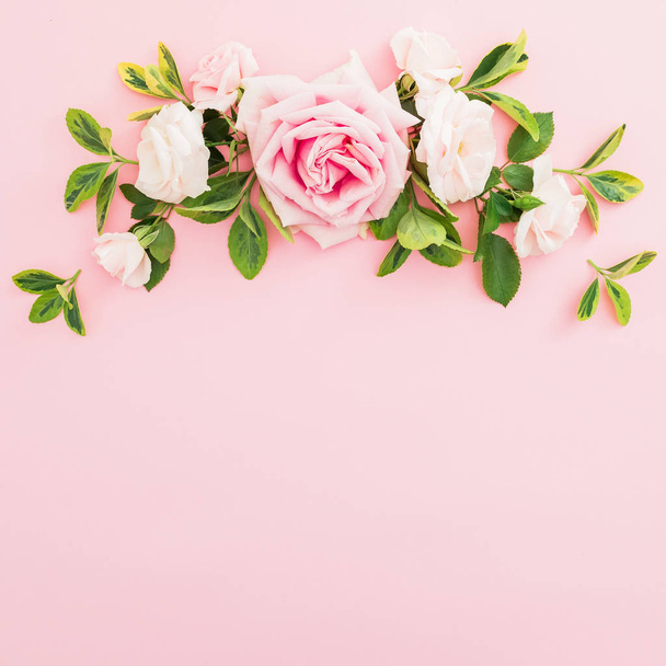 Composición del marco con rosas rosadas y hojas sobre fondo rosa pastel. Piso tendido, vista superior
. - Foto, imagen