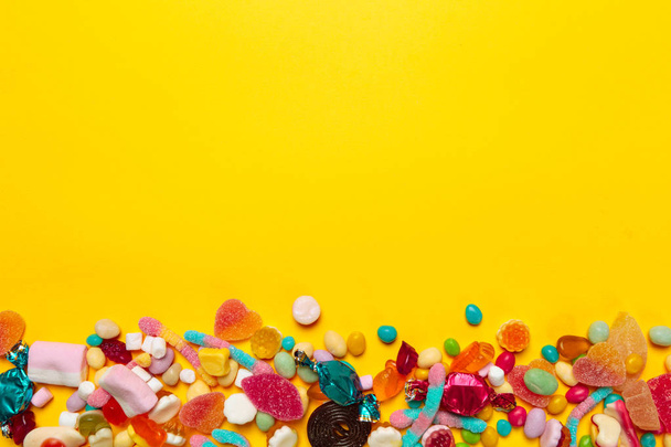 colored candies on yellow background - Φωτογραφία, εικόνα