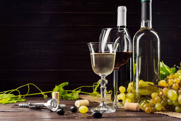 Wine bottle and grape on wooden table - Фото, изображение