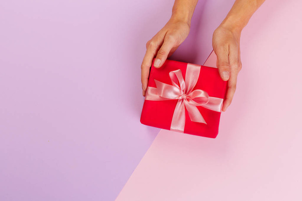 Женщина держит подарочную коробку на цветном фоне
 - Фото, изображение