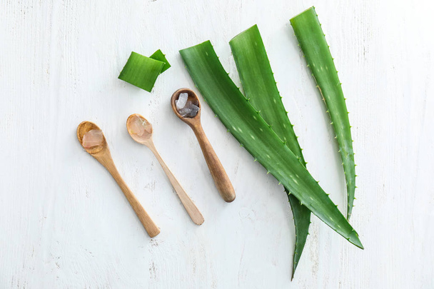Spoons with peeled aloe vera and green leaves on white table - Fotoğraf, Görsel