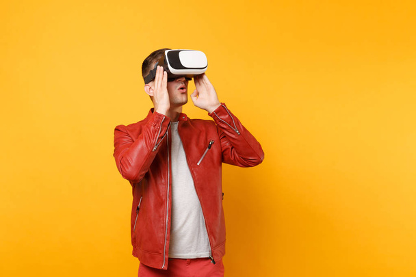 Portrait vogue fun young man in red leather jacket t-shirt looking up in headset standing isolated on bright trending yellow background. People sincere emotions lifestyle concept. Advertising area - Foto, Bild