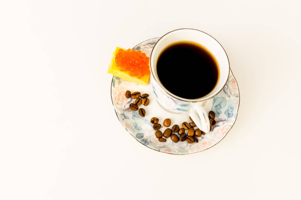 coffee, black or with milk in a Cup, on a saucer, on a white table, on a saucer are cheese and caviar  - Φωτογραφία, εικόνα