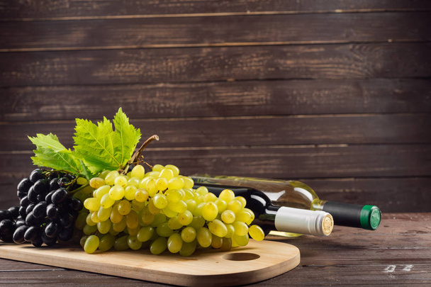 Botella de vino y uva en mesa de madera
 - Foto, imagen