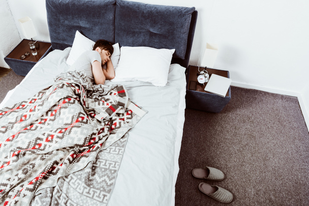 自宅のベッドで寝ている若い男のハイアングル  - 写真・画像