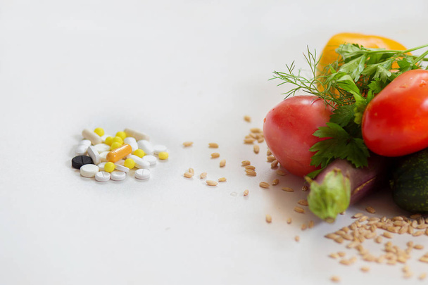 Φάρμακα που βρίσκονται απέναντι από τα λαχανικά σε λευκό φόντο - Φωτογραφία, εικόνα