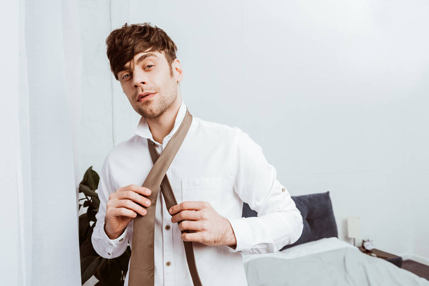 foco seletivo de homem de negócios em camisa branca amarrando gravata pescoço em casa
 - Foto, Imagem