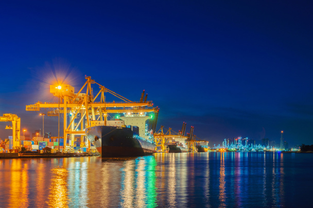 Containervracht schip tijdens het exporteren en importeren van bedrijfs- en logistiek internationale goederen in stedelijke stad. Verschepen van vracht naar de haven door crane bij zonsondergang. - Foto, afbeelding