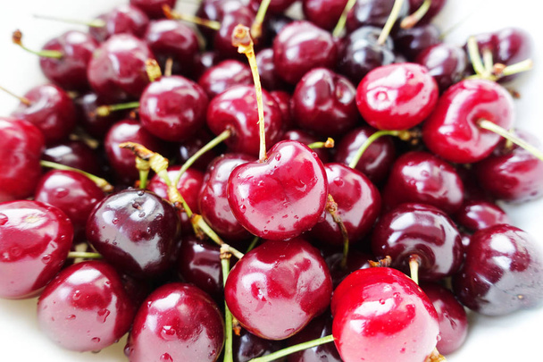 Macro shot of freshly picked cherries with green leaves, food texture or background - Foto, Imagem