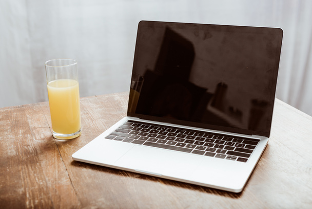 close up view of laptop with blank screen and orange juice at table  - Фото, изображение