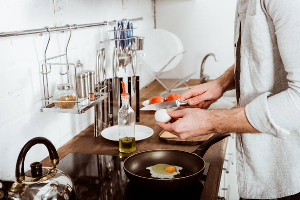若い男が台所で朝食のスクランブルエッグを料理の画像をトリミング  - 写真・画像