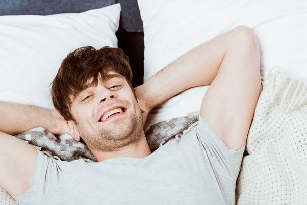 portrait de jeune homme regardant la caméra et couché au lit le matin à la maison
 - Photo, image