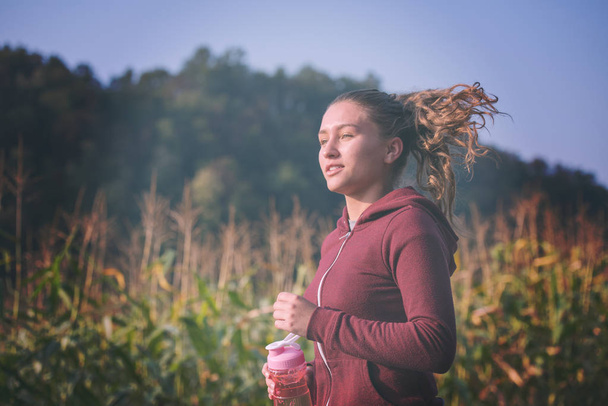 young woman enjoying in a healthy lifestyle while jogging along a country road, exercise and fitness concept - Fotó, kép