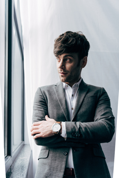 pensive young businessman in jacket looking away in office - Foto, Imagem