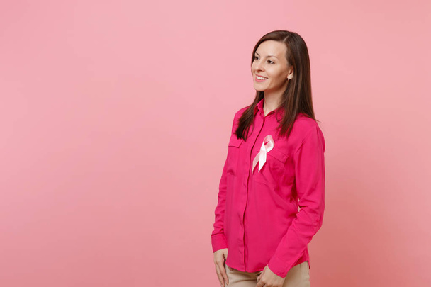 Frau in rosafarbener Kleidung mit rosafarbenem Seidenband-Symbol auf pastellfarbenem Hintergrund, Studioporträt. medizinisches Gesundheitswesen gynäkologische Onkologie, Brustkrebs-Aufklärungskonzept. Attrappe Kopierraum - Foto, Bild