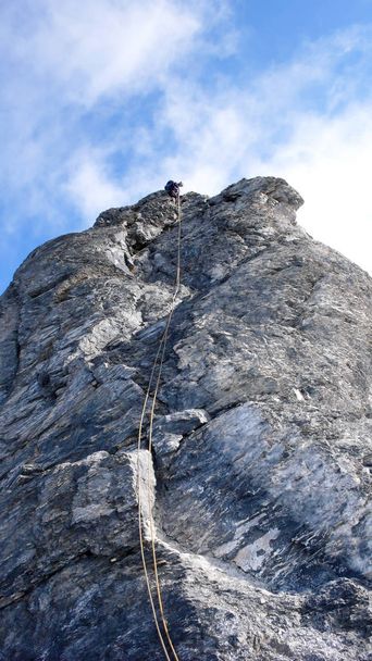 альпинист мужского пола на крутом маршруте скалолазания в швейцарских Альпах возле Клостерса
 - Фото, изображение