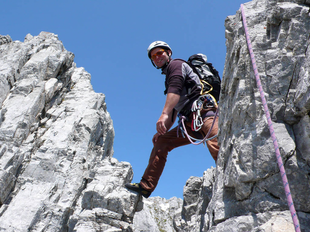 男性登山クロスタース近くスイス アルプスのルートを登る急な岩の上 - 写真・画像