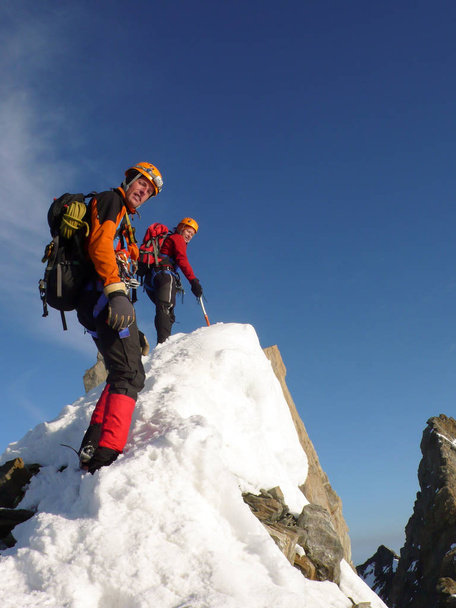 płci męskiej i żeńskiej alpinista na narażonych rocky summit ridge w drodze do wysoki alpejski szczyt - Zdjęcie, obraz
