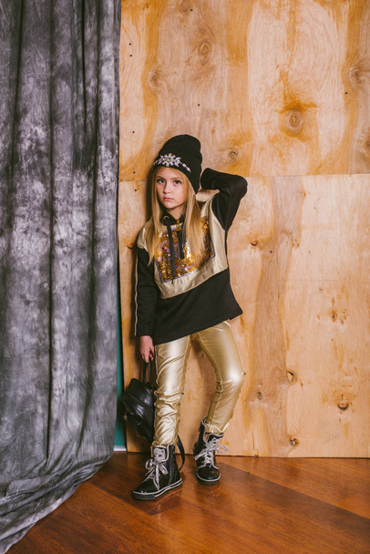 Little cute girl with blond hair in fashionable leggings, with gold and sequins, with a backpack - Фото, зображення